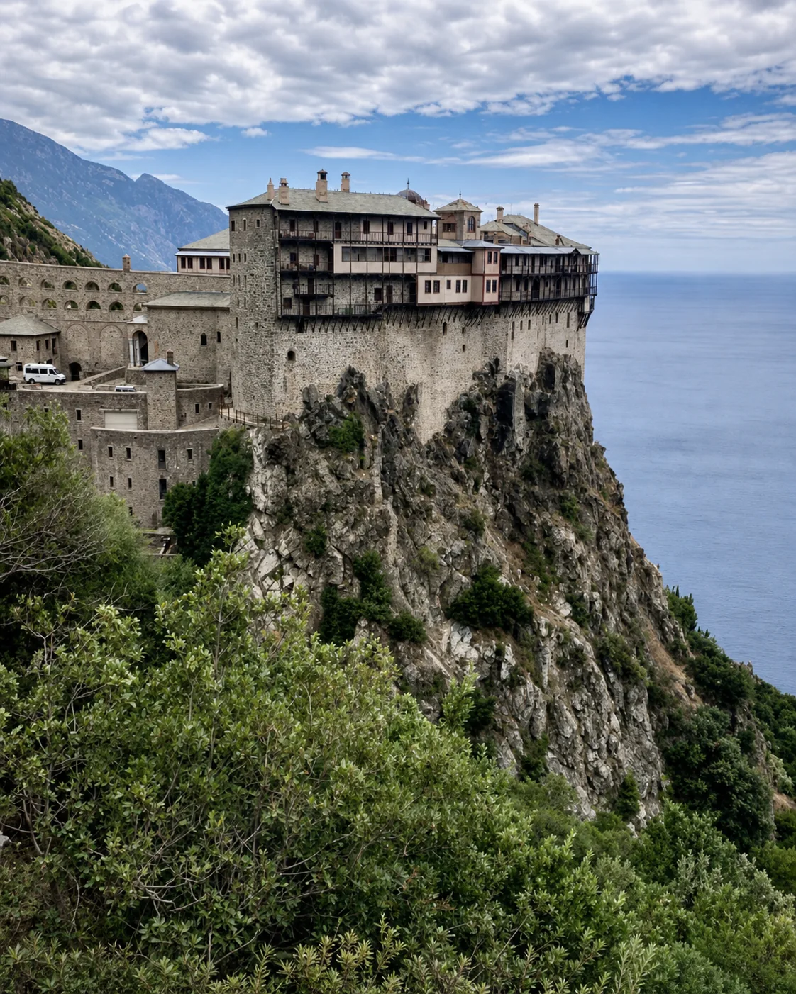 Monastic buildings rising above the rocky, forested coast of Mount Athos